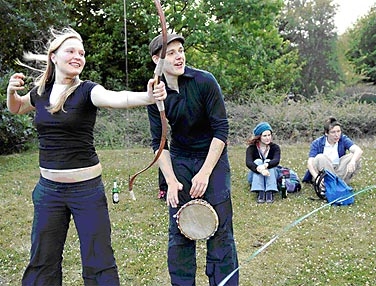 Eine junge Frau mit einem Bogen und ein junger Mann mit kleiner Trommel