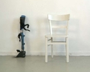 Ein Prothese lehnt an eine Wand. Daneben steht ein weisser Stuhl.