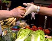 Zwei Händer die etwas übergeben über einer Salat- und Gemüseauslage