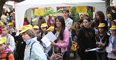 Kinder mit gelben Mützen des Stöbertages laufen  mit Studierenden vor einem Zelt her.