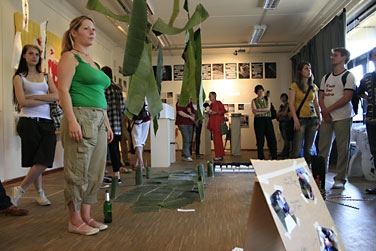 BesucherInnen der Ausstellung in den Kunsträumen stehen zwischen Kunstobjekten auf dem Boden und von der Decke hängend.