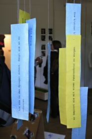Von der Decke hängen Papierstreifen mit Drehbuchpassagen im Kunstraum