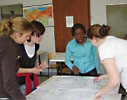 SchülerInnen in einem Klassenraum arbeiten an einer Landkarte