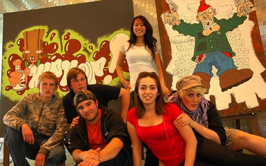 6 Jugendliche aus dem Rap-Workshop des Xenos-Projekts „Born to be Me - Für Vielfalt und Demokratie“ posieren vor einer Wand mit Graffiti-Bild