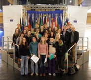 Gruppenfoto auf dem Promi-Podest im Europaparlament vor EU-Flaggen.