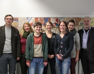 Dieses Foto zeigt das FSPE Team, welches aus sieben Personen besteht. Diese stehen auf einem Gruppenbild nebeneinander. Im Hintergrund ist eine weiße Wand mit einem bunten Bild zu sehen.