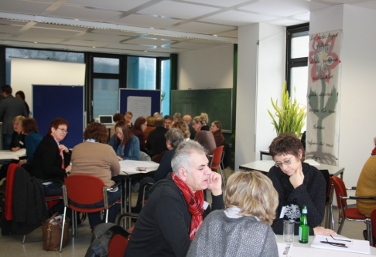 Die Teilnehmden an der Tagung führen die World-Café-Methode durch, das heißt, sie sitzen an mehreren Tischgruppen im Konferenzraum und tauschen sich aus.