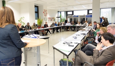 Das Bild zeigt die Diskussion im Plenum - alle Teilnehmer_innen sitzen im Konferenzraum an einem U-förmigen Tisch
