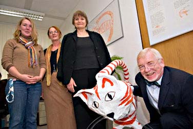 Vier Menschen stehen um eine orange-weiss gestreifte Tigerfigur