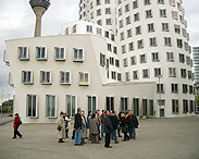 Gruppe vor den Gehry Häusern im Medienhafen mit Rheinturm im Hintergrund